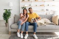 Young affectionate multiracial couple sitting on couch with pet dog and watching television at home Royalty Free Stock Photo