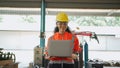 Young Africa American engineer wearing safety helmet and glasses holding the laptop and walking and smile in the robotic arm