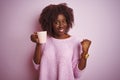 Young african afro woman holding cup of coffee standing over isolated pink background screaming proud and celebrating victory and Royalty Free Stock Photo