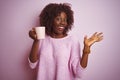 Young african afro woman holding cup of coffee standing over isolated pink background very happy and excited, winner expression Royalty Free Stock Photo