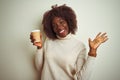 Young african afro woman holding cup of coffee standing over isolated white background very happy and excited, winner expression Royalty Free Stock Photo