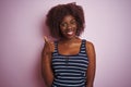 Young african afro woman wearing striped t-shirt glasses over isolated pink background doing happy thumbs up gesture with hand Royalty Free Stock Photo