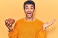 Young african amercian man holding bowl with almonds celebrating achievement with happy smile and winner expression with raised Royalty Free Stock Photo