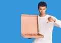 Young african amercian man holding delivery pizza box with angry face, negative sign showing dislike with thumbs down, rejection Royalty Free Stock Photo