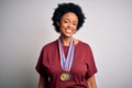 Young African American afro athlete woman with curly hair wearing medals for competition with a happy and cool smile on face