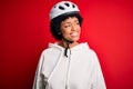 Young African American afro cyciling woman with curly hair wearing bike security helmet looking away to side with smile on face, Royalty Free Stock Photo