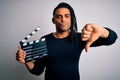 Young african american afro director man making movie using clapboard with angry face, negative sign showing dislike with thumbs