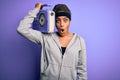 Young african american afro girl listening to music holding vintage radio over purple background scared in shock with a surprise Royalty Free Stock Photo