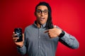 Young african american afro man holding broken smartphone showing craked screen with surprise face pointing finger to himself Royalty Free Stock Photo