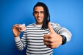 Young african american afro man holding plastic teeth with dental braces happy with big smile doing ok sign, thumb up with Royalty Free Stock Photo