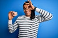 Young african american afro man holding plastic teeth with dental braces with happy face smiling doing ok sign with hand on eye Royalty Free Stock Photo