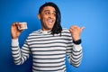 Young african american afro man holding plastic teeth with dental braces pointing and showing with thumb up to the side with happy Royalty Free Stock Photo