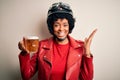Young African American afro motorcyclist woman with curly hair drinking jar of beer very happy and excited, winner expression Royalty Free Stock Photo