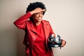 Young African American afro motorcyclist woman with curly hair holding motorcycle helmet very happy and smiling looking far away Royalty Free Stock Photo