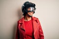 Young African American afro motorcyclist woman with curly hair wearing motorcycle helmet looking away to side with smile on face, Royalty Free Stock Photo