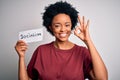 Young African American afro politician woman with curly hair socialist party member doing ok sign with fingers, excellent symbol