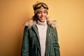 Young african american afro skier girl wearing snow sportswear and ski goggles winking looking at the camera with sexy expression, Royalty Free Stock Photo