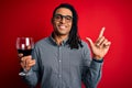 Young african american afro sommelier man with dreadlocks drinking glass of wine surprised with an idea or question pointing Royalty Free Stock Photo