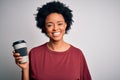 Young African American afro woman with curly hair drinking cup of coffee with a happy face standing and smiling with a confident Royalty Free Stock Photo
