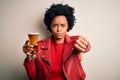 Young African American afro woman with curly hair drinking glass of beer with alcohol with angry face, negative sign showing Royalty Free Stock Photo