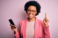 Young African American afro woman with curly hair having conversation using smartphone surprised with an idea or question pointing Royalty Free Stock Photo