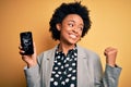 Young African American afro woman with curly hair holding cracked broken smartphone pointing and showing with thumb up to the side