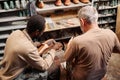 Young African American apprentice of shoemaker fixing upper part of boot