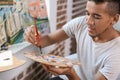 Young African-American artist painting picture in workshop Royalty Free Stock Photo