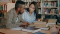Young african american and asian college students working together preparing for exams while sitting at table at Royalty Free Stock Photo