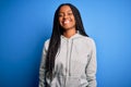 Young african american athlete woman wearing sports sweatshirt over blue isolated background with a happy and cool smile on face