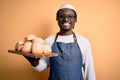 Young african american baker man wearing apron holding tray with homemade bread with a happy face standing and smiling with a Royalty Free Stock Photo