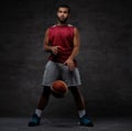 Young African-American basketball player in sportswear playing with ball. Isolated on a dark background. Royalty Free Stock Photo