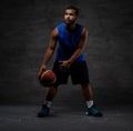 Young African-American basketball player in sportswear playing with ball. Isolated on a dark background. Royalty Free Stock Photo