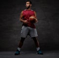 Young African-American basketball player in sportswear playing with ball. Isolated on a dark background. Royalty Free Stock Photo