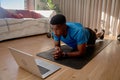 Young African American black male athlete watching workout videos on his laptop doing an online class while holding