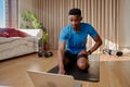 Young African American black male about to attend an online exercise class using his laptop, sitting on a yoga mat