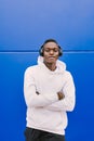 Young African American black man listening music with wireless headphones while wearing a white sweatshirt, looking to camera Royalty Free Stock Photo