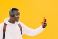 Young african American black man looking at smart phone while listening music with wireless headphones. Taking self portrait, self Royalty Free Stock Photo