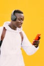 Young african American black man looking at smart phone while listening music with wireless headphones Royalty Free Stock Photo