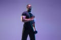 Young african-american bodybuilder training over purple background in neon, mixed light Royalty Free Stock Photo