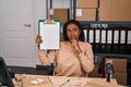 Young african american with braids working at small business ecommerce showing clipboard serious face thinking about question with