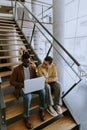 Young African American business man and short hair woman working on laptop while sitting at office stairs Royalty Free Stock Photo
