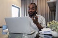 Young African American business man working with laptop and document on desk and talking on mobile at home Royalty Free Stock Photo