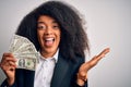 Young african american business woman with afro hair holding cash dollars banknotes very happy and excited, winner expression Royalty Free Stock Photo