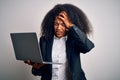 Young african american business woman with afro hair using computer laptop from job stressed with hand on head, shocked with shame