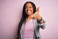 Young african american business woman standing over pink isolated background smiling friendly offering handshake as greeting and Royalty Free Stock Photo