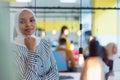 Young African American business woman standing and smiling. Happy successful business leader posing while her team in background