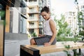 Young African American business woman working on laptop, looking at screen of a smartphone on urban background . Female Royalty Free Stock Photo