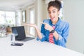 Young african american business woman working using computer laptop amazed and smiling to the camera while presenting with hand Royalty Free Stock Photo