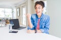 Young african american business woman working using computer laptop smiling with happy face looking and pointing to the side with Royalty Free Stock Photo